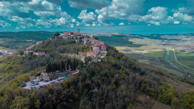 Hırvatistan 'ın İstria kentindeki muhteşem Motovun köyünün hava aracı görüntüsü. Güneşli bir günde hoş, tüylü bulutlar. Idyllic view of picoresque istrian village