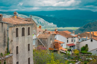 Motovun tepesinden Mirna nehrine bakan panoramik manzara bulutlu bir günde. Önde kırmızı çatılar ve kilise var.