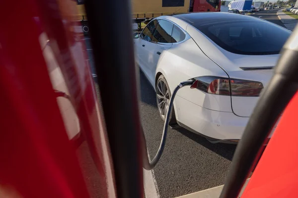 Charging an electric car. Modern electric car being charged on a fast charger on a motorway rest stop or gas station.