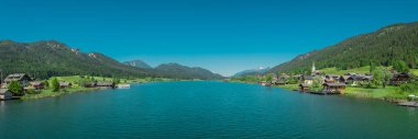 Avusturya 'da Weissensee gölünün güzel kıyıları, yazın sıcağında alp gölü olan güzel bir zemin. Ortadaki köprüden geniş bir manzara alındı..