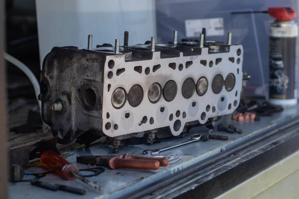 Old cylinder head of a 8V diesel engine sitting on a bench or atable. Visible combustion side of a cylinder head, just milled or straightened.