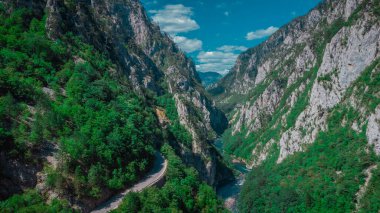 Vadi üzerindeki yüksek yol köprüsüne yakın Piva Nehri Kanyonu 'nun dar geçidi. Arka planda yeşil dikey kaya oluşumları ve mavi gökyüzü, Durmitor ve Mratinje hidroelektrik barajına yakın..