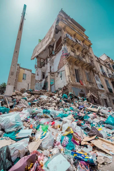 A huge amount of rubbish next to a partially collapsed building in Oran, Algeria on a sunny day. People still live in this house, altough half of it is destroyed.