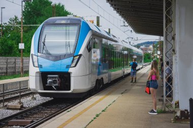 Young female is ready to hop on a train, waiting in on a platform, ready to enter. Nice young woman with sexy jeans shorts waiting for a train.