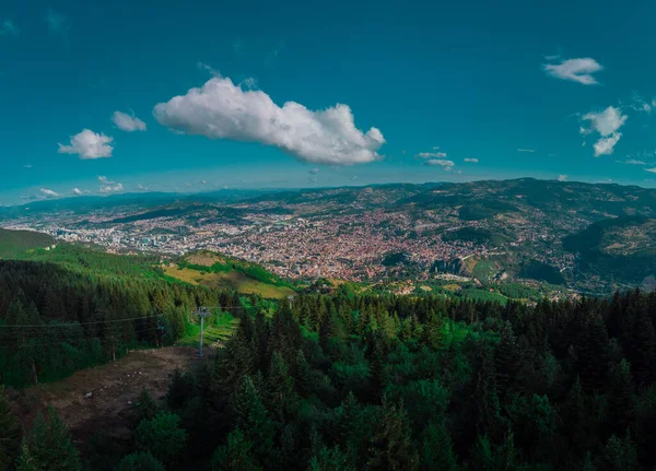 Aerial drone panorama of the city of Sarajevo on a summer day. Viewed from a vantage point close to upper station of gondola or cable car.