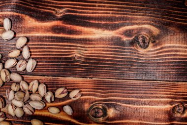 Bir avuç dolusu fıstık ahşap bir masaya saçılmış. yazıt için yer