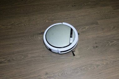 Operasyon sırasında otomatik robot elektrikli süpürge beyazdır. Yerleri temizler. Soldan sağa hareket