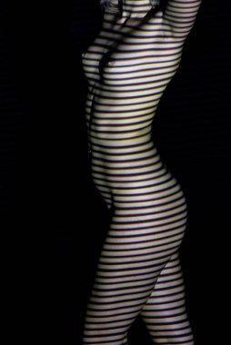 Işığın ve gölgelerin önünde çıplak kadın vücudu. Güzel bacaklar ve gövde.