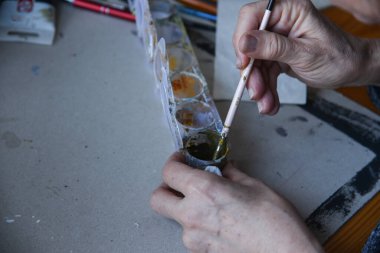 Akrilik renkleri karıştıran eller. Kirli boya tüpleri. Boya fırçalarını kapat. Boş kopyalama alanı