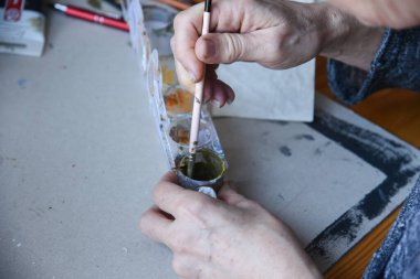 Akrilik renkleri karıştıran eller. Kirli boya tüpleri. Boya fırçalarını kapat. Boş kopyalama alanı