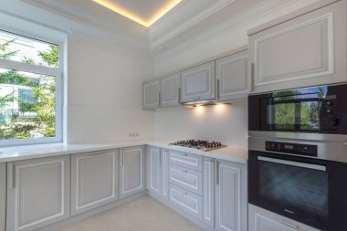Modern bright kitchen with a window and built-in furniture and appliances.