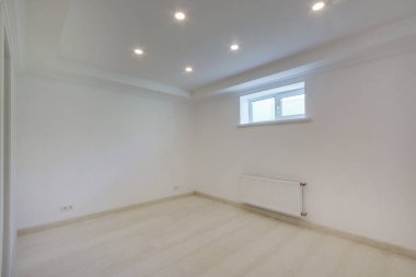 A bright room with light beige laminate and a small window.