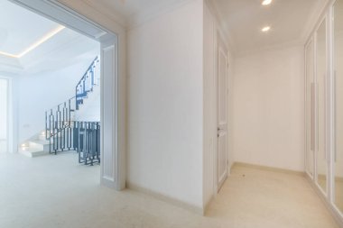 A bright hall with high ceilings, stairs and a mirrored door to the living room. New modern house without furnitur