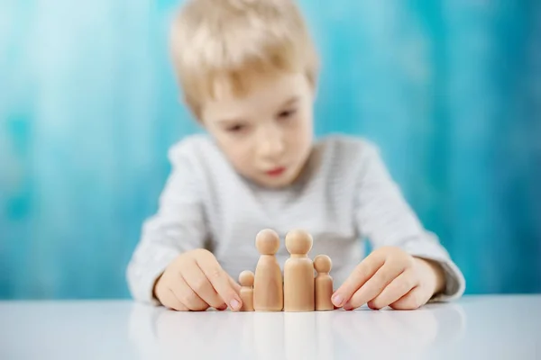 Gyermek játszik fa figurák a család a kék háttér — Stock Fotó