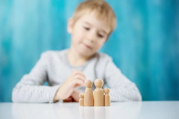 Kind mit Holzfiguren der Familie auf blauem Hintergrund — Stockfoto