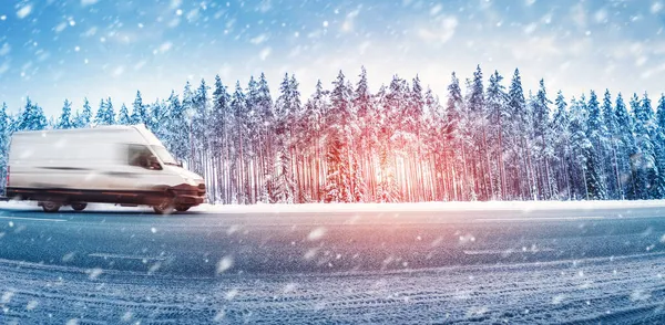 Furgoneta blanca moviéndose en un camino de asfalto resbaladizo en nevadas —  Fotos de Stock
