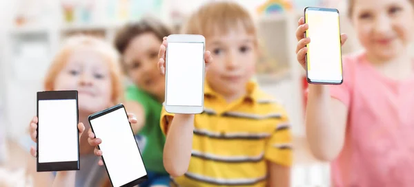 Група дітей тримає в руках смартфони з макетним екраном в приміщенні — стокове фото