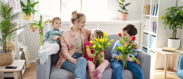 Cute cildren e sua mãe sentados com buncheson o sofá. — Fotografia de Stock