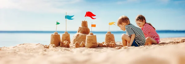 Jongen en meisje spelen op het strand tijdens de zomervakantie. — Stockfoto