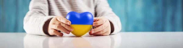 Jungenhände halten ein Herz in ukrainischen Farben — Stockfoto