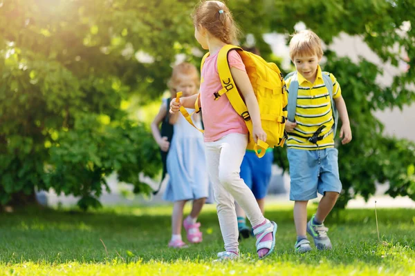 Crianças bonitos com mochilas andando no parque perto da escola — Fotografia de Stock