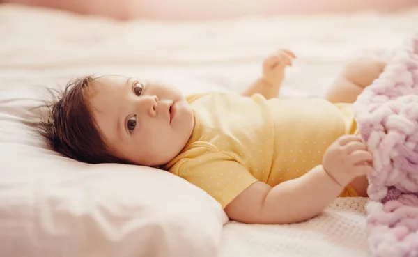 Χαριτωμένο μωράκι ξαπλωμένο κάτω από ροζ κουβέρτα. — Φωτογραφία Αρχείου