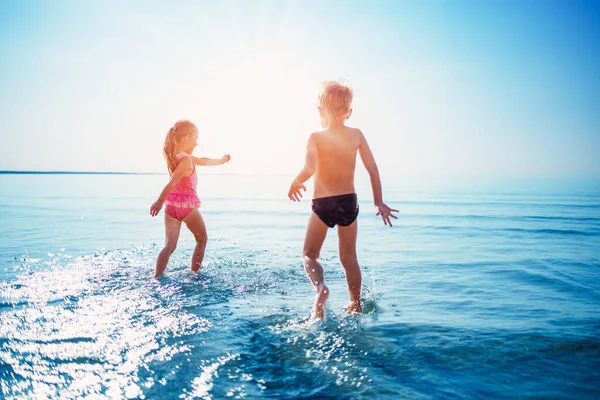 Happy children playing together in the sea in summer — Stockfoto