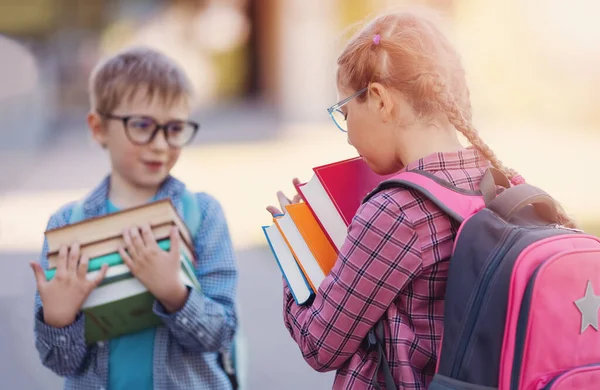 Girl and boy in glasses standing with books in their hands. Concept of back to school and studying.