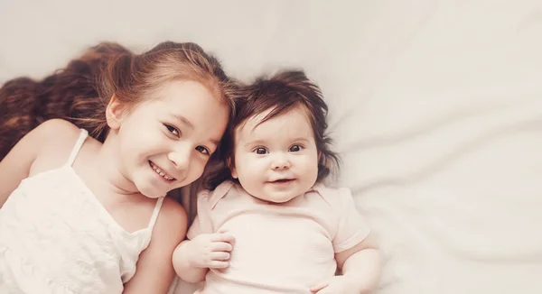 Two Sisters Smiling Lying White Blanket Indoors Concept Family Loving — 스톡 사진