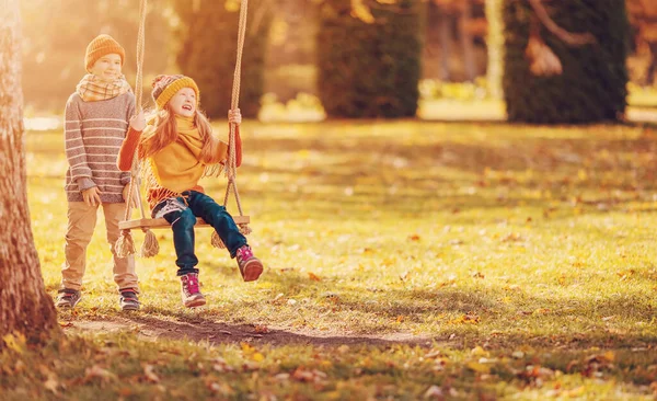Couple Children Playing Autumnal Park Boy Swinging Girl Swing Concept — 스톡 사진