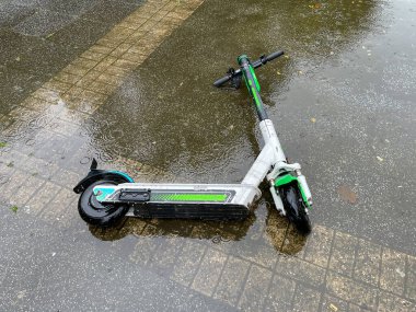 Electric scooter abandoned in water in puddle. clipart