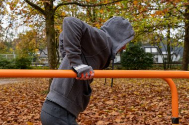 Antrenman, sporcu yatay çubuğu kaldırır, dışarıda, sonbaharda.