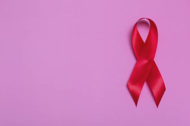 Kırmızı kurdele konseptiyle pembe arkaplan manzarası 1 Aralık Uluslararası AIDS Günü yakın plan.