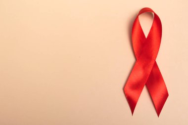 Uluslararası AIDS Günü. Bej arka planda kırmızı kurdele. Yakın plan. Banner. AIDS farkındalığı konsepti. 1 Aralık.