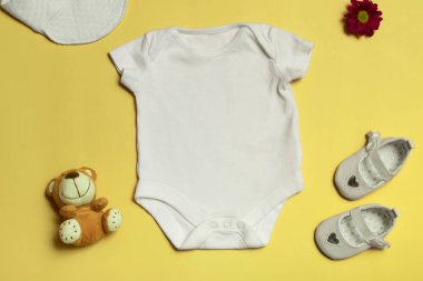 Logoların tasarımı ve yerleştirilmesi için bir model, reklamcılık. Beyaz bebek tulumu, üst manzara, sarı arka planda model al..