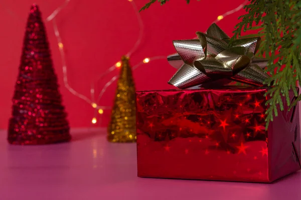 분홍색 배경에 크리스마스 트리 아래에 금색 리본이 달린 빨간 상자 안에 멋진 선물 이 있습니다. 새해와 크리스마스. 복사 공간 — 스톡 사진