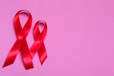 Kırmızı kurdele konseptiyle pembe arkaplan manzarası 1 Aralık Uluslararası AIDS Günü yakın plan.
