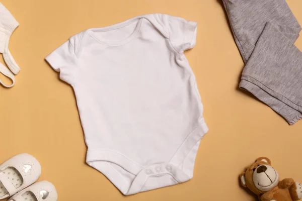 Logoların tasarımı ve yerleştirilmesi için bir model, reklamcılık. Beyaz bebek tulumu, üst manzara, sarı arka planda model al..