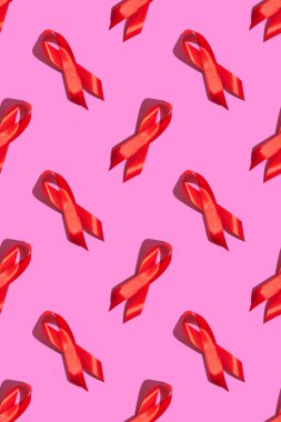 Uluslararası AIDS Günü. Pembe arka planda sert gölgeli kırmızı kurdele. AIDS farkındalığı konsepti. Dikey fotoğraf. Desen