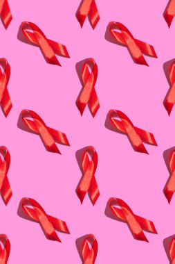 Uluslararası AIDS Günü. Pembe arka planda sert gölgeli kırmızı kurdele. AIDS farkındalığı konsepti. Dikey fotoğraf. Desen