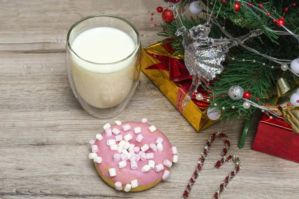 Noel çöreği ve Noel Baba için süt. Sütlü ve tatil süslemeli büyük bir bardak. Ahşap arka planda bir Noel içkisinin fotoğrafı.
