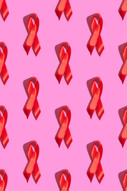 Uluslararası AIDS Günü. Pembe arka planda sert gölgeli kırmızı kurdele. AIDS farkındalığı konsepti. Dikey fotoğraf. Desen