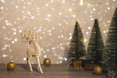Noel ve Yeni Yıl dekoru. Noel geyiği, süslemeler ve Noel ışıkları olan ahşap bir arka planda Noel ağaçları. Noel kartını kapat.