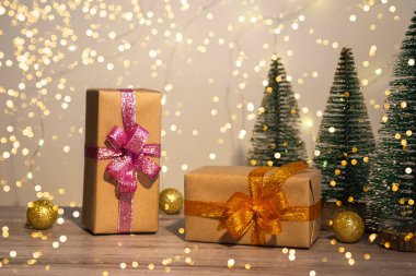 Noel ve Yeni Yıl dekoru. Noel hediyeleri, dekorasyonlar ve Noel ışıkları olan ahşap bir arka planda yeni yıl ağaçları. Noel kartını kapat.