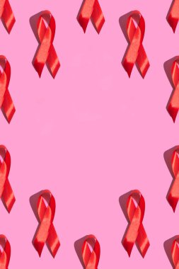 Uluslararası AIDS Günü. Pembe arka planda sert gölgeli kırmızı kurdele. AIDS farkındalığı konsepti. Dikey fotoğraf. Örnek. kopyalama alanı ile