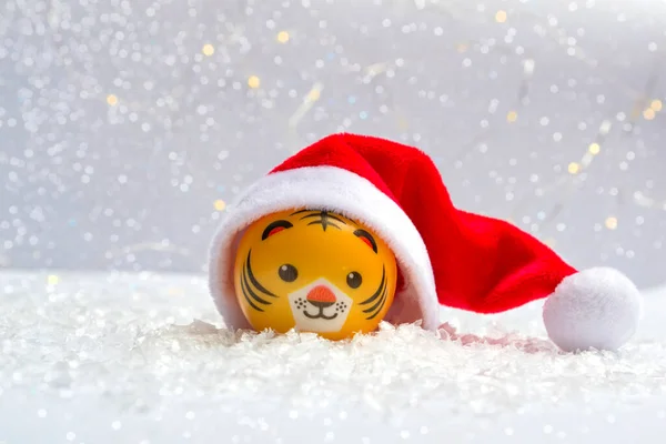 Yeni yılın sembolü, kar üzerinde Noel Baba şapkası takmış bir kaplan ve arka plandaki Bokeh ışıkları. Yeni yıl konseptini kapat