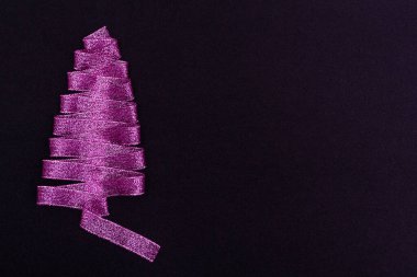 Noel konsepti. Siyah arkaplandaki kurdelelerden yapılmış mor Noel ağacı. Kartpostallar, ambalajlar, reklamlar için kopya alanı şablonu ile.
