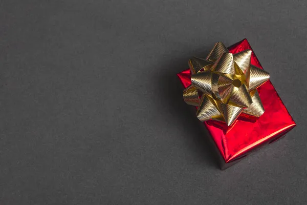 Beautiful gift red box with a gold bow on a black background close up, top view, with copy space Royalty Free Stock Photos