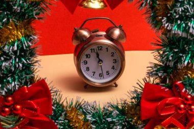 Kapatın. Süslemeli Noel çelengi ve renkli bir arka planda çalar saat. Boşluğu kopyala.