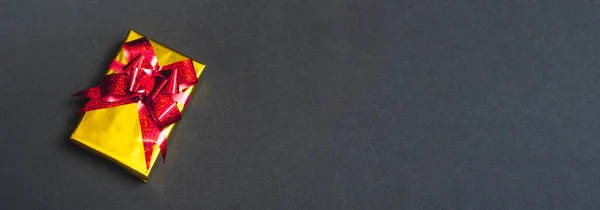 黒の背景のクローズアップ トップビューに赤い弓を持つ美しいギフトの金の箱 コピースペース — ストック写真